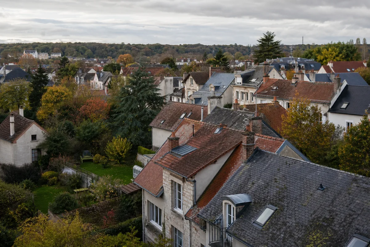 Toitures pavillonnaires en tuile plate et ardoise sous un ciel changeant dans les Yvelines